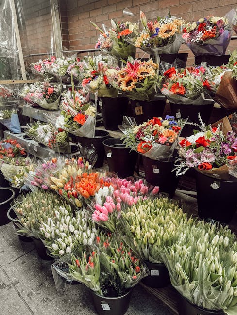 A retail display of numerous flower bouquets and arrangements at Flowers Nine Elms, situated in an indoor space with exposed brick walls and large windows. The bouquets include a variety of fresh flow